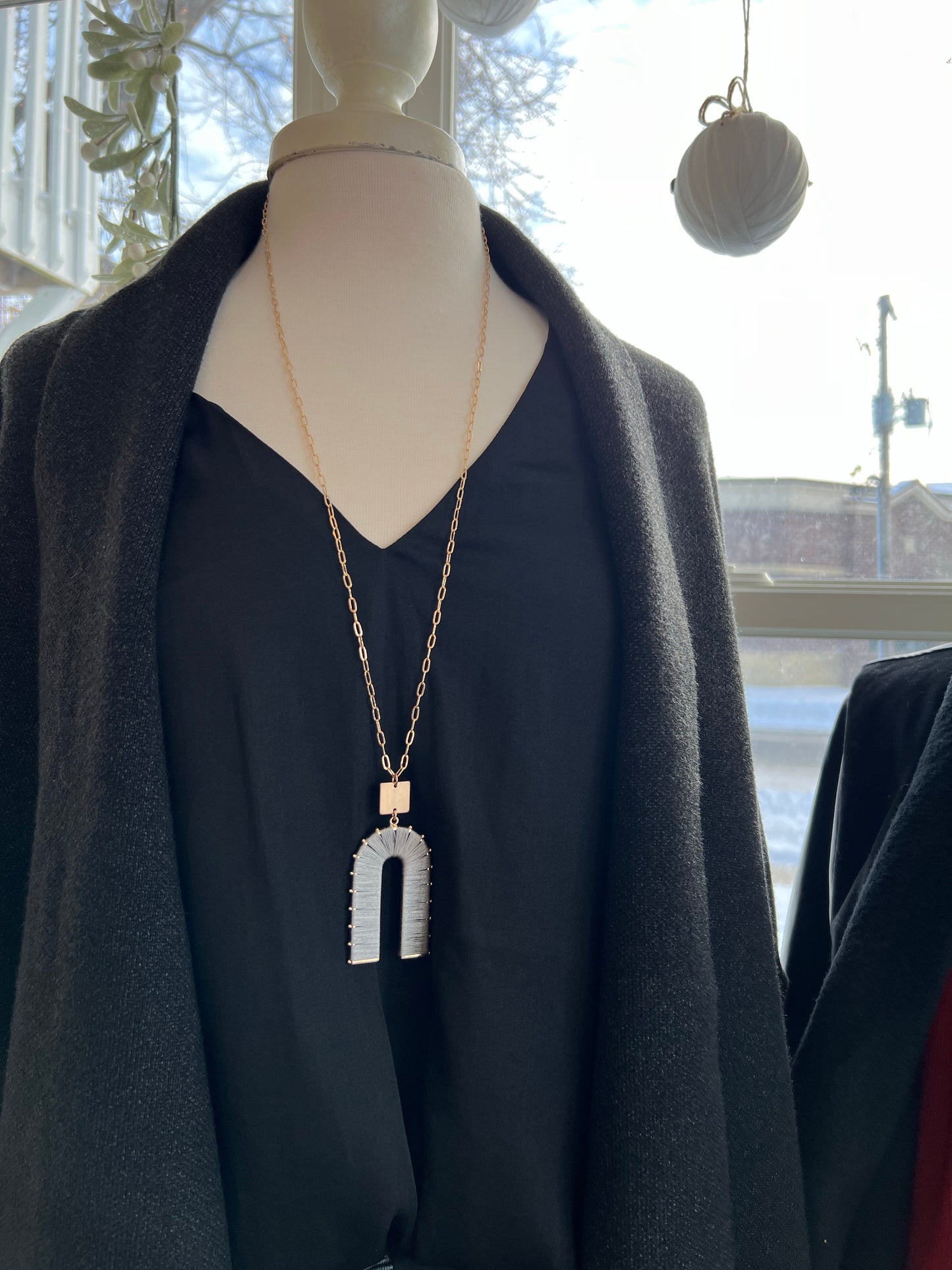 An upside down U shape charm with a gold chain. 32" necklace.